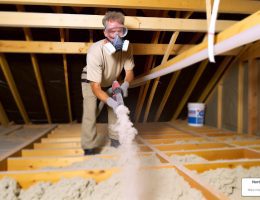 Northeast Home & Energy employee uses a hose to distribute insulation in attic